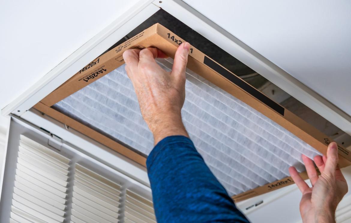 Person installing new air filter in vent
