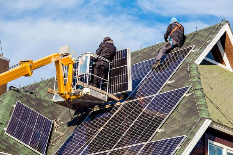Workers putting solar panels onto roof